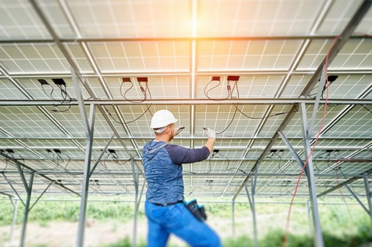 Técnico verificando cabeamento sob painéis solares